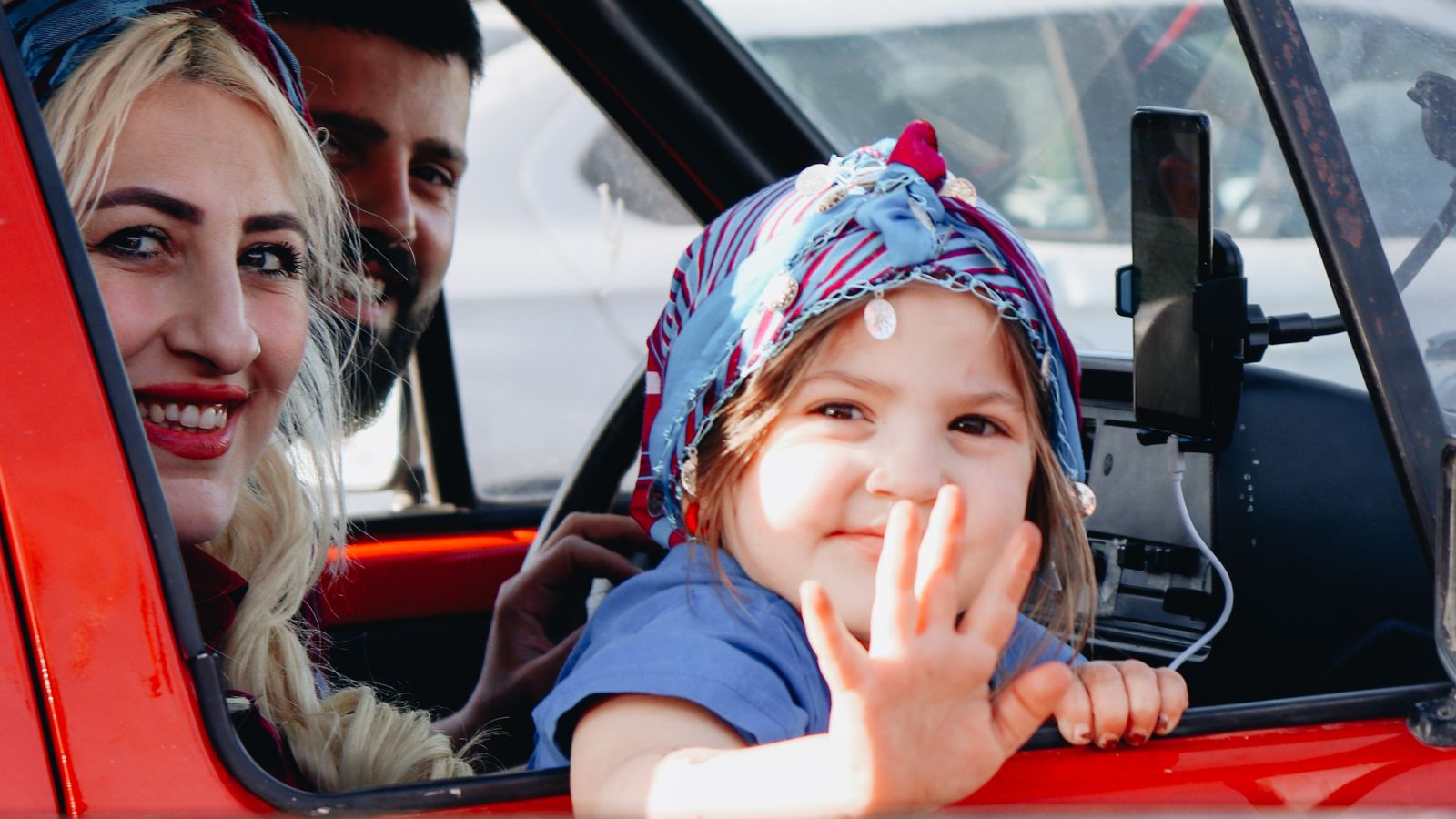A family with a young child in a car on a sunny day