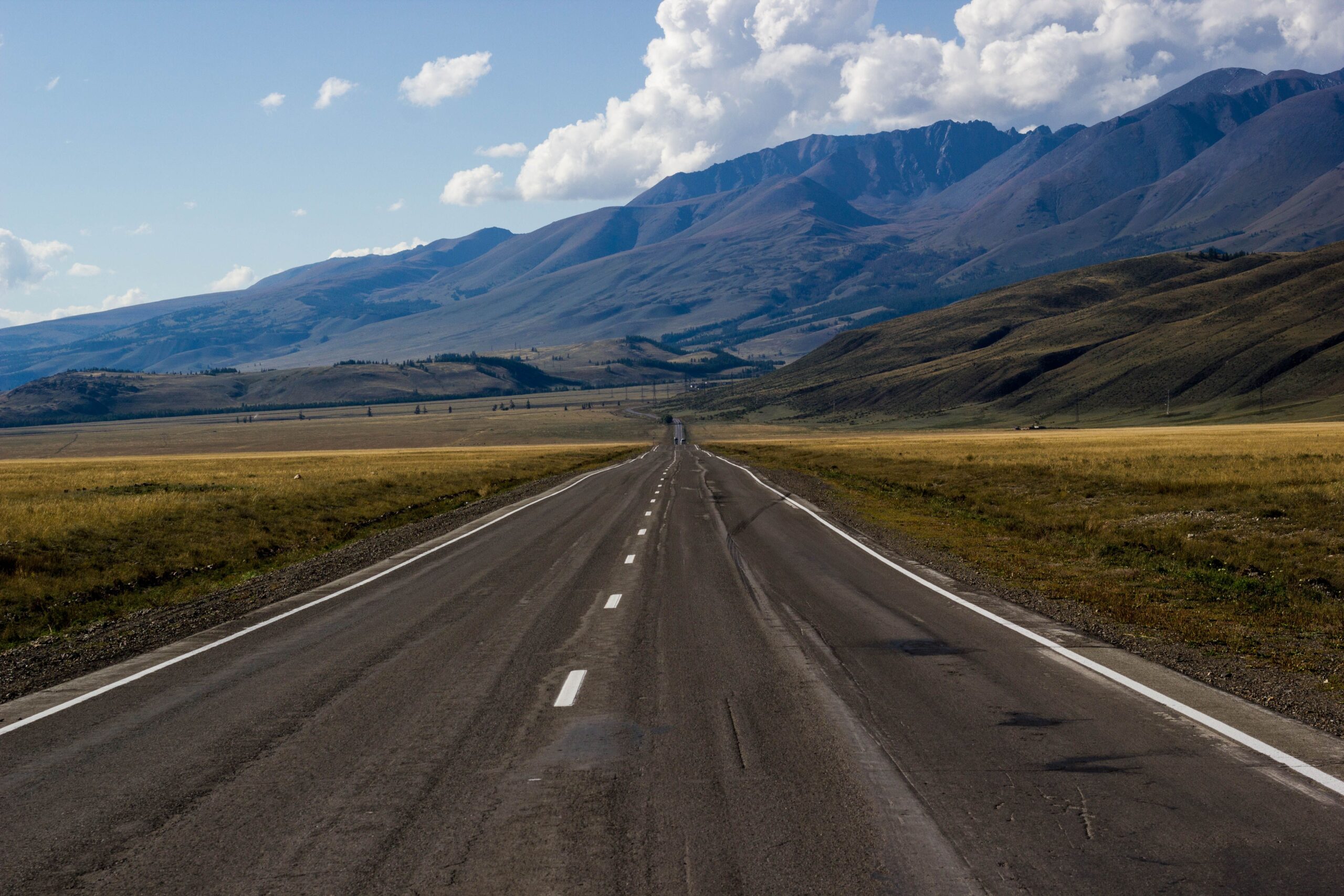 Empty highway curving toward distant mountains at first light
