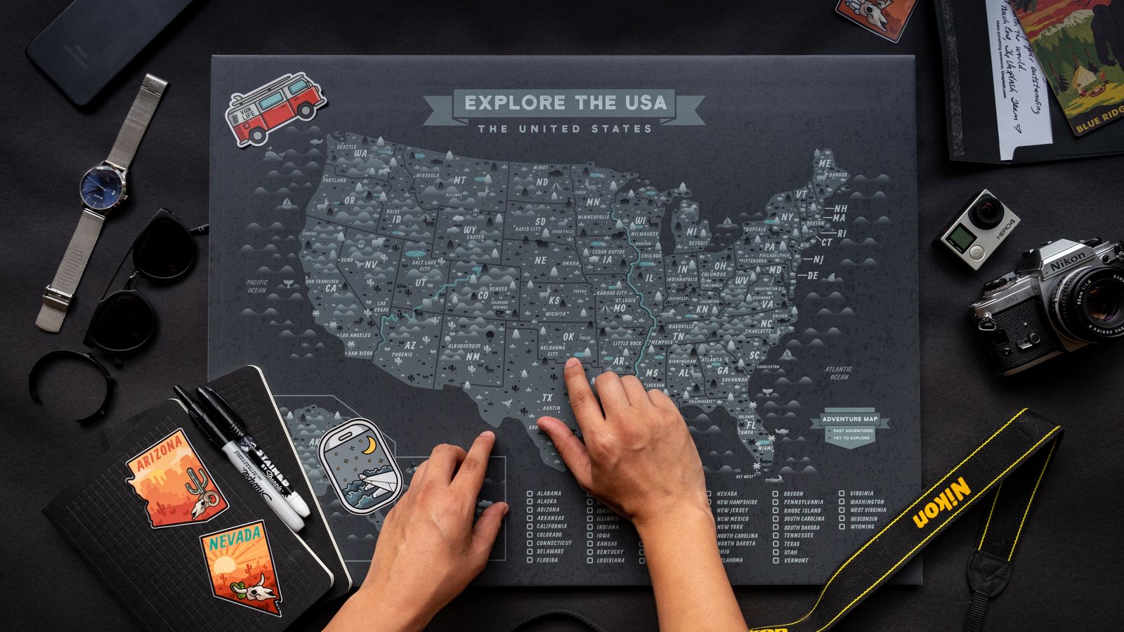 Hands planning a route on a map of the USA with a notebook
