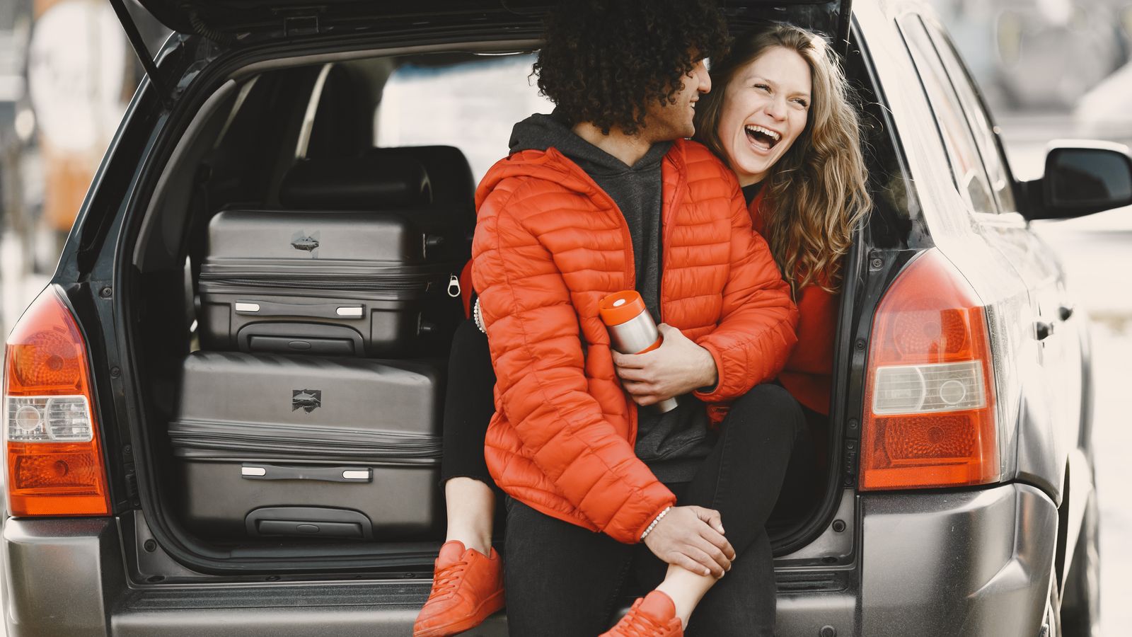 Travelers with luggage packed in the open trunk of a car